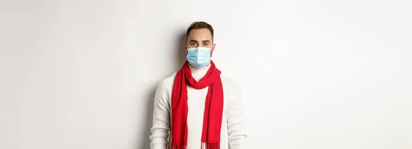 Covid ロックダウンと隔離の概念 若いです男で冬のセーターと医療マスク立って白い背景 — ストック写真