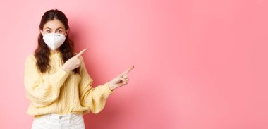 Covid, Corona ve sosyalleşme konsepti. Solunum cihazındaki heyecanlı kadın modeli size reklam veriyor, logoyu gösteriyor, yüzüne tıbbi solunum cihazı takıyor, pembe arka plan..