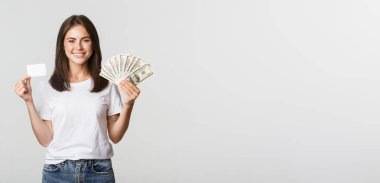 Heyecanlı gülümseyen kızın portresi. Elinde para ve kredi kartı var..