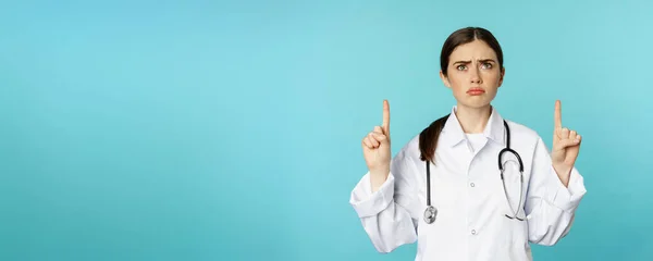 Médica Triste Sombria Trabalhadora Médica Amuada Apontando Olhando Para Cima — Fotografia de Stock