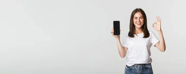 Agradável Sorridente Morena Menina Mostrando Tela Smartphone Mostrando Gesto Aprovação — Fotografia de Stock