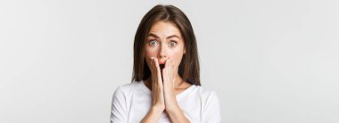 Şok olmuş esmer kızın yakın çekimi elleri ile ağzını kapatıyor..