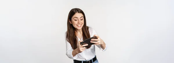 Щаслива Брюнетка Граючи Мобільну Відеогру Посміхаючись Дивлячись Екран Збуджена Стоїть — стокове фото