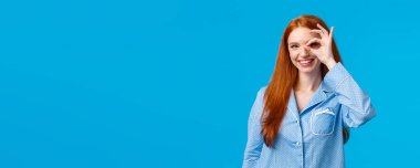 Mükemmel bir seçim. Karizmatik tatmin olmuş, gece elbisesi giymiş, güzel jest yapan, güzellik ürünlerini tanıtan, adet dönemini dert etmeyen, mavi arka planda duran kızıl saçlı bir kadın..