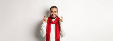 Noel tatili ve yeni yıl konsepti. Umut dolu bir adam dua ediyor, hediyeler bekliyor, beyaz arka planda duruyor..