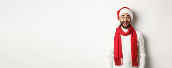 クリスマス休暇だ 白い背景に立って サンタパーティーの帽子と赤いスカーフを着て カメラを見て驚いた髭の男 — ストック写真