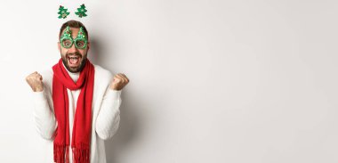 Noel, yeni yıl ve kutlama konsepti. Heyecanlı adam ödülü, kış terfisi, yumruk tokuşturma ve kutlama, parti gözlüğü, beyaz arka plan.