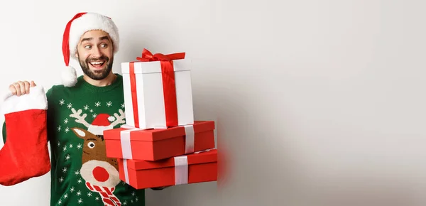 圣诞节和寒假的概念 兴奋的男人拿着圣诞袜和礼品盒 站在白色的背景上庆祝新年 — 图库照片
