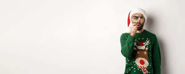 크리스마스와 호기심많은 남자가 확대경을 뭔가를 있었어요 모자를 Xmas 스웨터를 있었죠 — 스톡 사진