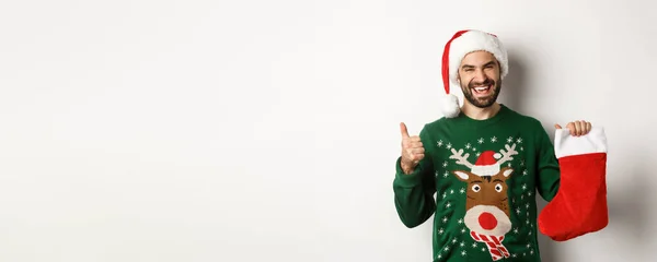 クリスマスと冬の休暇の概念 クリスマスの靴下の贈り物が好き親指を立てて白い背景の上に立つ — ストック写真
