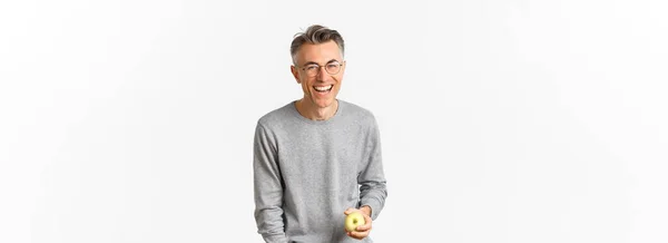 一个快乐健康的中年男人的形象 拿着绿色的苹果 无忧无虑的笑着 站在白色的背景上 — 图库照片