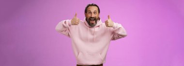 Heyecanlı, destekleyici, karizmatik Avrupalı, pembe kapüşonlu, olgun sakallı adam gülümsüyor. Gülümsüyor, gülümsüyor..