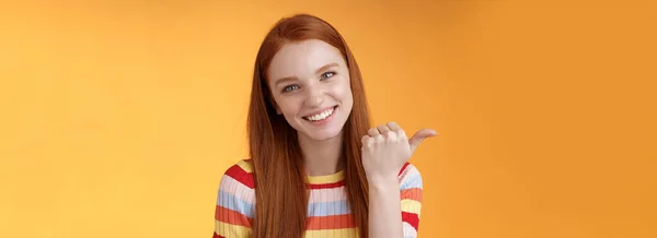 友善温柔的女性 红头发的女人蓝眼睛 手指左边显示找到产品复制空间的位置 这有助于讨论有趣的发笑的发亮的橙色背景 — 图库照片