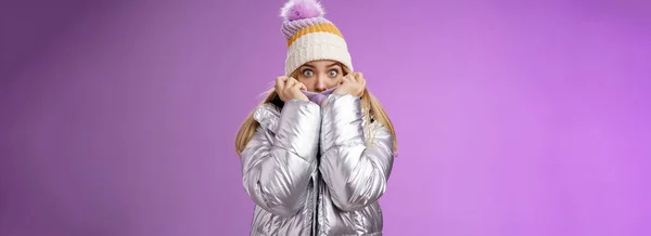 恐怖ショックを受けた若い魅力的な妹のジャケットの顔を引っ張るカバーを非表示に恐ろしい恐ろしい話を怖がらせる雪だるまの山々を歩くと 紫色の背景に立って 目のカメラの恐怖を懸念 — ストック写真