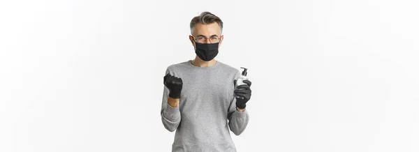 コロナウイルスの概念 ライフスタイルと隔離 医療用マスクと手袋の明るい白人男性のイメージは 手の消毒剤を示し 喜びに拳ポンプを作り 白い背景の上に立って — ストック写真