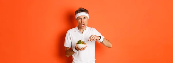 Portrait Angry Middle Aged Male Athlete Eating Salad Looking Disturbed — Stock Photo, Image