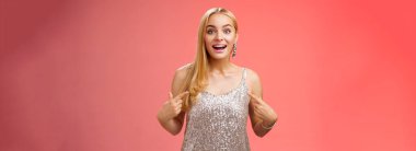 Şaşırmış, mutlu, çekici, gümüşten elbisesi olan, neşeli, neşeli, neşeli, neşeli bir kadın seçilmiş, harika bir etkinliğe katılmış, neşeli, kırmızı arka planda kalmış..