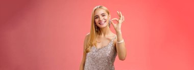 İyimser, çekici, şık, gümüşten elbise giymiş sarışın bir kadın. Tamam, gülümseyen bir jest olsun. Güzelce onaylayın..