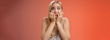 Korkmuş, genç, sarışın, paniklemiş, tırnak yiyen, patlak gözlü, korkmuş kamera dehşete düşmüş, nutku tutulmuşa benziyor..