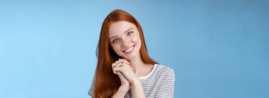 Romantik, narin, kızıl saçlı, başını yana eğmiş, basın avuçlarını birbirine dayamış, gülümseyen, sempatik bakışlı, sevimli, neşeli, içten bir şekilde duran arkadaş resmine bak..