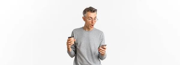 Gri Süveter Gözlüklü Kahve Içen Cep Telefonu Ekranına Bakıp Internetten — Stok fotoğraf