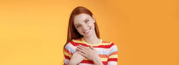 stock image Pleased tender feminine good-looking redhead woman receive compliment confession touch heart feel warmth dearest moment smiling delighted lovely keep love inside soul, standing orange background.