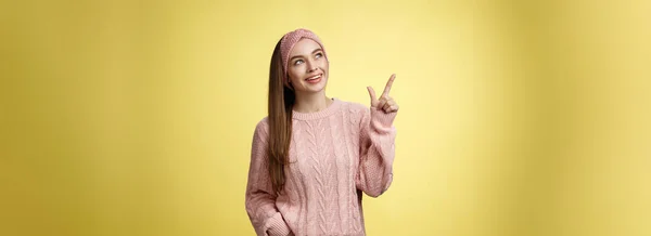 面白い面白いかわいい20代のヨーロッパの女の子の肖像はセーターを着て 左上隅を見てヘッドバンドは横に笑顔を指して興味深い 恍惚と 黄色の壁に好奇心プロモーションによってキャプチャ — ストック写真