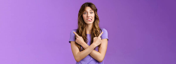 Perplexed timid hesitant worried girlfriend afraid making bad choice cross hands pointing sideways indicating left right perplexed decide frowning pull hesitant face asking advice purple background