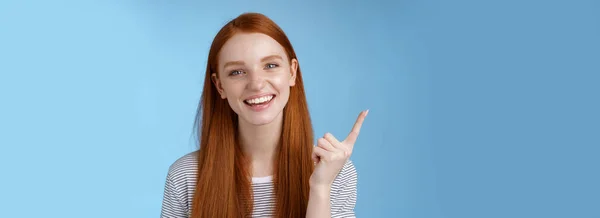 幸せなカリスマ性のある赤毛笑って若い女の子楽しい見てのんきな話新製品販売指数指を指しています上のコピースペース広告 立って青い背景 — ストック写真