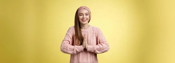 お願いだから ニットセーターを着た魅力的な若い女性学生 一緒に祈る物乞いで手のひらを押すヘッドバンド 笑顔感謝の気持ちを助けるために求めて 黄色の壁の努力に感謝 — ストック写真