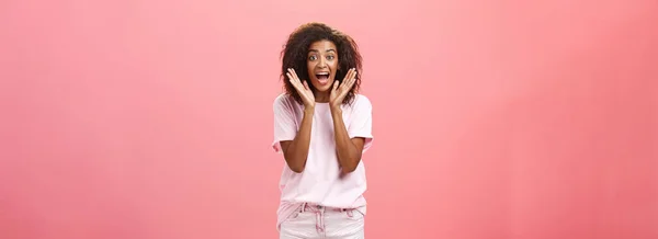 stock image Indoor shot of expressive excited attractive dark-skinned adult woman in casual outfit yelling from amazement and joy holding palms near face reacting on awesome news with excitement and happiness