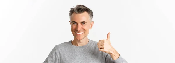 一个英俊 穿着灰色毛衣的中年男子的特写镜头 大拇指翘起表示赞同 推荐一些东西 站在白色背景之上 — 图库照片