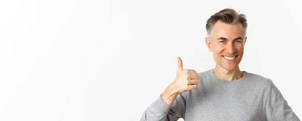 一个英俊 穿着灰色毛衣的中年男子的特写镜头 大拇指翘起表示赞同 推荐一些东西 站在白色背景之上 — 图库照片