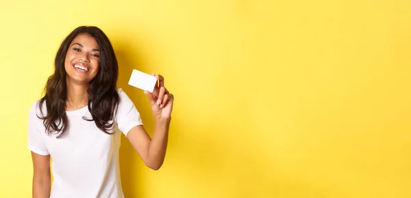 stock image Image of lovely african-american woman smiling happy, showing credit card, standing over yellow background.