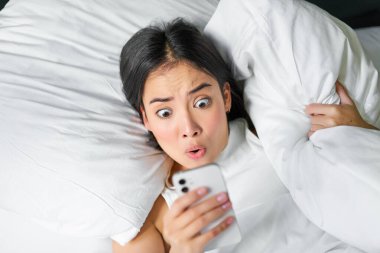 Asyalı bir kızın portresi sabah uyanır, şok olmuş yüzüyle cep telefonuna bakar, uyuyakalır, yastığa sarılır ve yüzünü buruşturur..