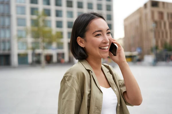 현대의 아시아인 소녀는 도시의 거리에서 전화로 이야기를 스마트폰으로 전화하면서 — 스톡 사진