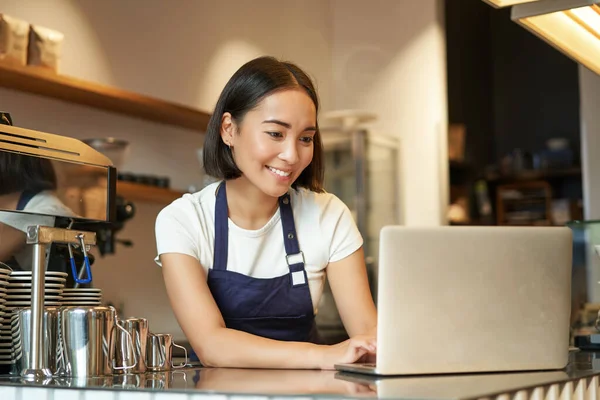笑顔のアジアのバリスタの肖像 カフェのオーナー起業家 ラップトップで作業し コンピュータ上で注文を処理し カウンターの後ろに立って — ストック写真