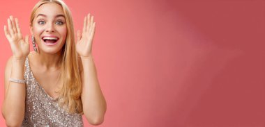 Etkileyici, çekici, sarışın, Avrupalı 25 'li yaşlarda, şık, güler yüzlü, neşeli, güler yüzlü, güler yüzlü, kırmızı arka planda duran bir kadın..