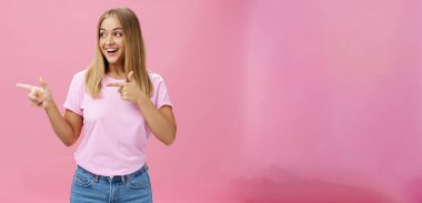 Mutlu, neşeli, tombul, açık renk saçlı, mutlu bir gülümsemeyle soldan sağa bakan pembe arka plandaki ilginç fotokopi alanına dönüp olumlu duygular ifade eden bir kız..