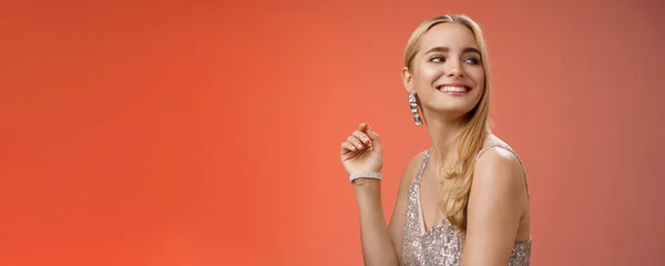 Elegant glamour gorgeous young rich blond woman attend charity party in stylish silver glittering dress accessorize turning right smiling greeting familiar person grinning joyfully, red background.