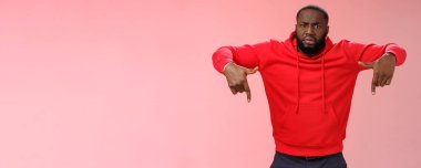 Questioned displeased pissed handsome serious-looking athletic black guy bearded frowning look perplexed wondered freak out pointing down waiting explanation, standing frustrated pink background.