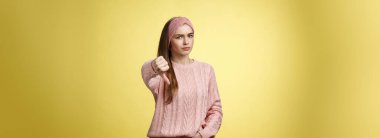 Hiç hoş değil. Hüsrana uğramış ve hoş olmayan, örgü örülmüş süveter giyen hoş bir kadın. Kaşları çatık, ters sırıtan, yargılayıcı bir tavır sergiliyor. Sarı duvardaki kötü durumu onaylamadığını belirtiyor..