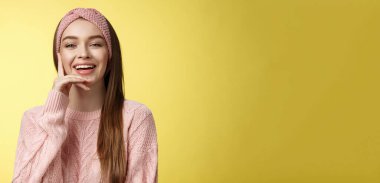 Neşeli genç, çekici Avrupalı kadın örgülü pembe saç bandıyla, kazağı yanaklarına değen, gülümseyen, gülen. Yüzünde gülümseme olan öğrenci, eğleniyor, komedi filminde kıkırdıyor..