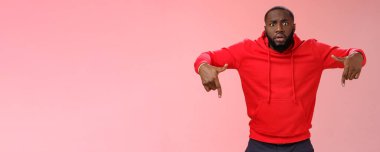 Sinirli, genç, sakallı, Afro-Amerikan, geniş gözlü, şok olmuş, umudunu kaybetmiş, endişeli, pari 'sini kaybetmiş, kırmızı kapüşonlu, pembe arka plan giymiş. Boşluğu kopyala