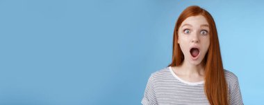 Vay canına, çok havalı. Etkilenmiş, komik, çekici, kızıl saçlı kız, mavi gözler, ağzı açık, ağzı açık, ağzı açık, ağzı açık, ağzı açık, şaşkın, mavi arka planda dikilen şaşkınlığı ifade ediyor. Boşluğu kopyala