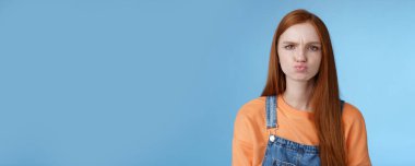 Huysuz, huysuz, yapışkan, mavi gözlü, somurtan, suratını asan, suratını asan, tavrını ekşiten, tatmin olmamış, mavi arka planda hayal kırıklığına uğramış, şikayetçi bir kız arkadaş..