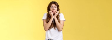 Ürkek, kendine güveni olmayan Avrupalı kız kıvırcık saç kesimi. El ele tutuşmuş, ısıran parmaklar. Korkmuş, sersemlemiş, nutku tutulmuş, korkudan titreyen sarı arka plan..