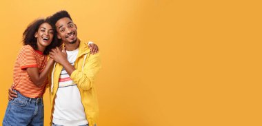 Arkadaşlar her zaman birbirlerini kollarlar. Zarif ve kaygısız sevecen Afrikalı Amerikalı kız arkadaşı erkek arkadaşına sarılıyor ve gülümsüyor. Avuç içlerine dokunuyor ve birlikte harika vakit geçiriyorlar..