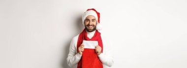 Kış tatili ve alışveriş konsepti. Yakışıklı sakallı adam Noel çorabında hediyeler getiriyor, gülümsüyor ve mutlu yıllar diliyor, beyaz bir geçmişi var..