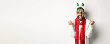 Noel, yeni yıl ve kutlama konsepti. Heyecanlı adam ödülü, kış terfisi, yumruk tokuşturma ve kutlama, parti gözlüğü, beyaz arka plan.